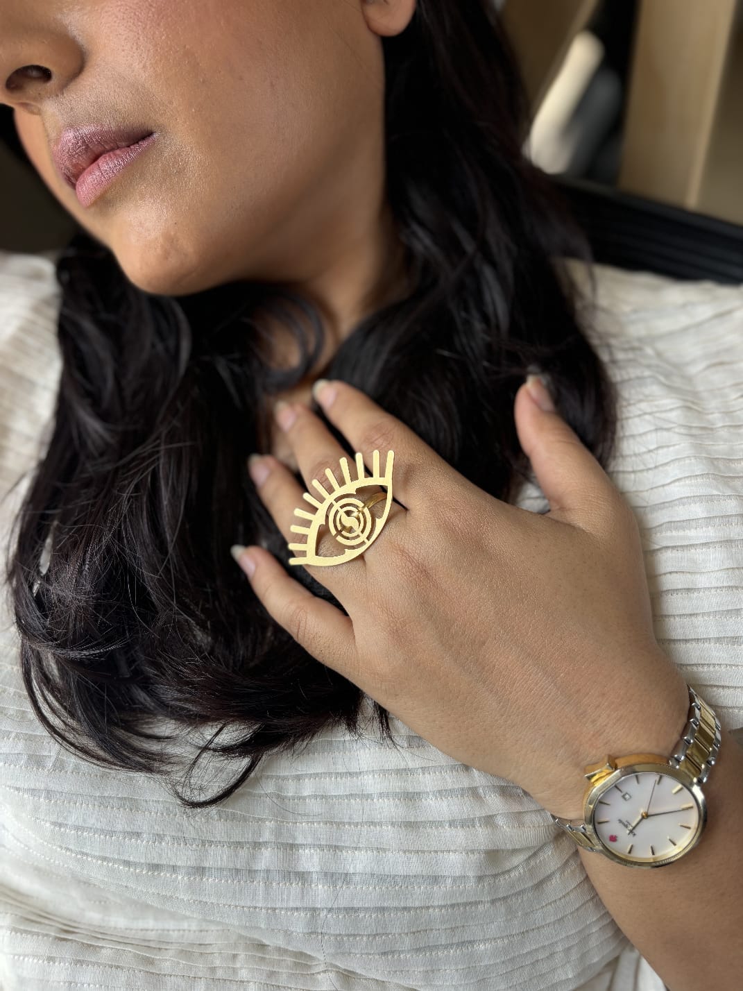 Close-up of a person wearing a gold ring and watch, with a blurred background.